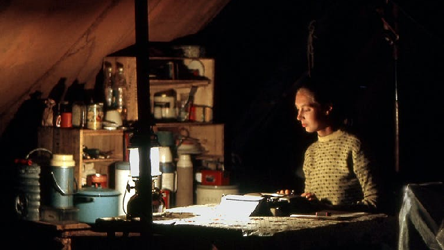 A young Jane Goodall writing up field notes in the dark in a tent in Gombe