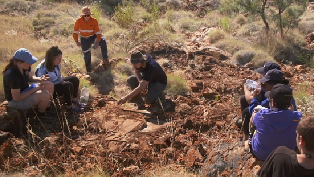Students in Pilbara crouched looking for ancients signs of life and fossils