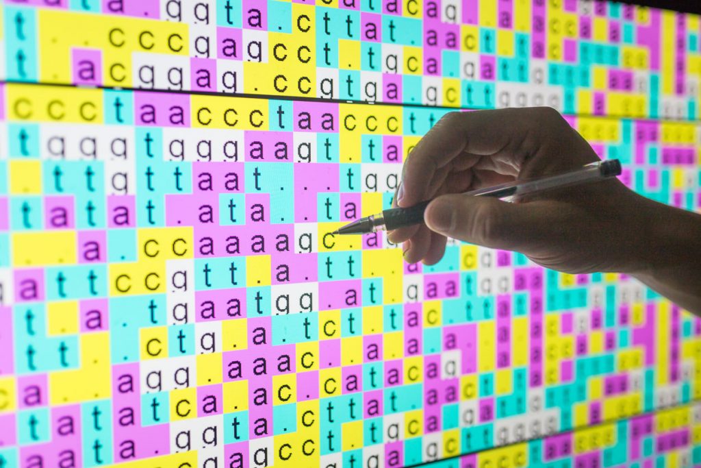 DNA code on screen with one hand touching the screen